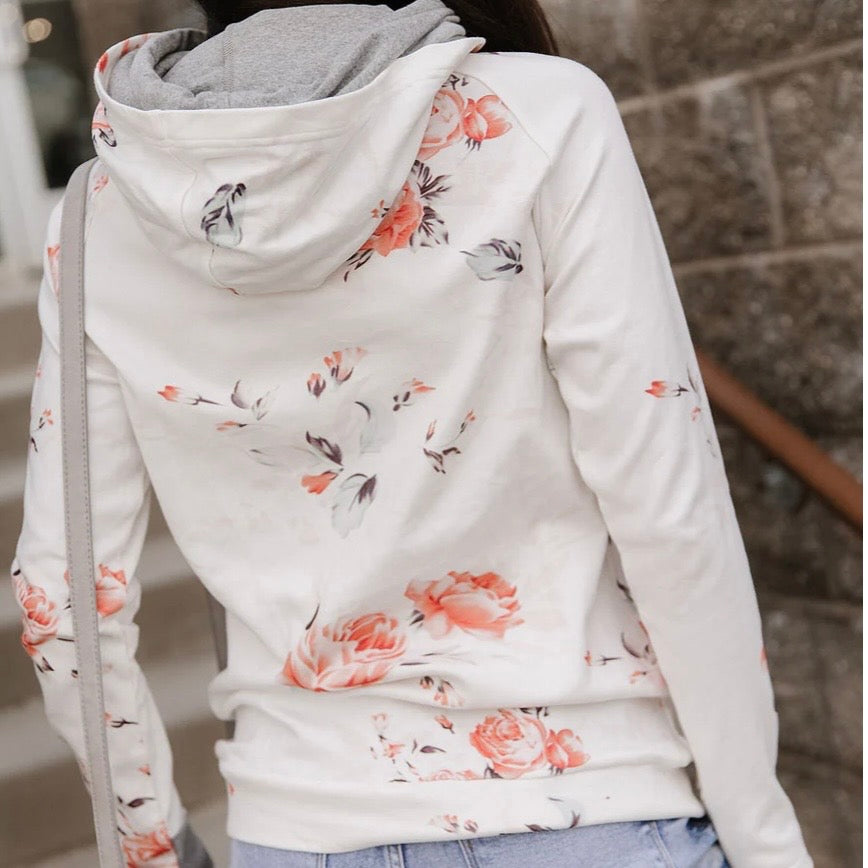 Floral-patterned hoodie worn by a person, with a blurred background