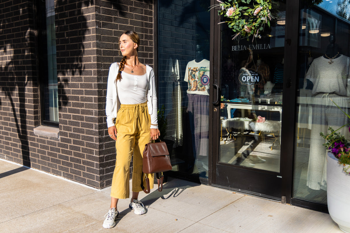 Full-length view of Uliana Leon wearing mustard wide-leg pants outside Bella Emilia Boutique.