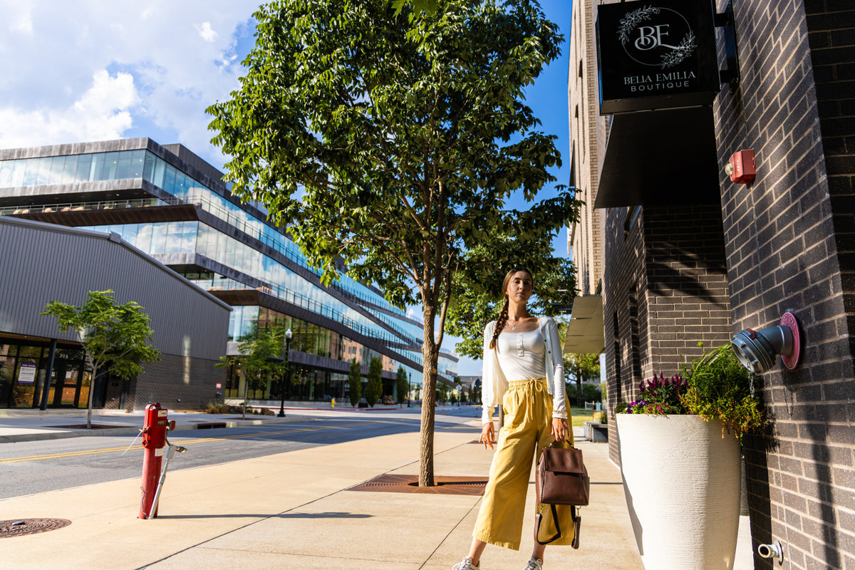 Uliana Leon in mustard wide-leg pants on a downtown Bentonville street.