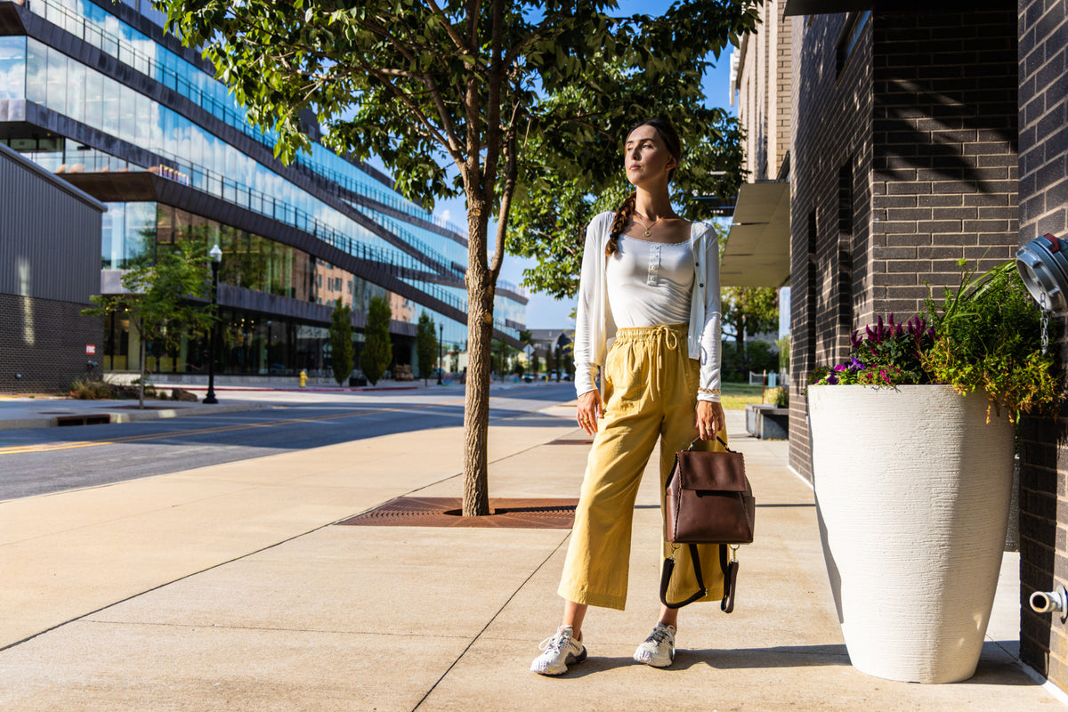Uliana Leon styles mustard wide-leg pants with a white top and brown bag in Bentonville.