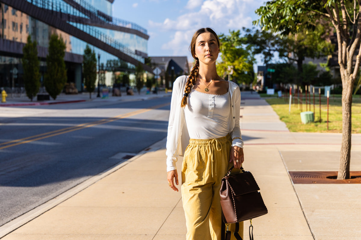 Close lifestyle view of the mustard wide-leg pants worn by Uliana Leon.