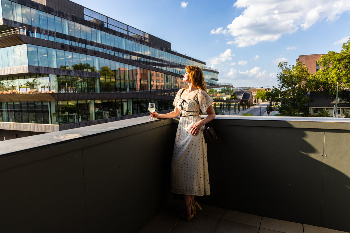 Cream bow print midi dress with flutter sleeves and black piping, full-length outdoor view